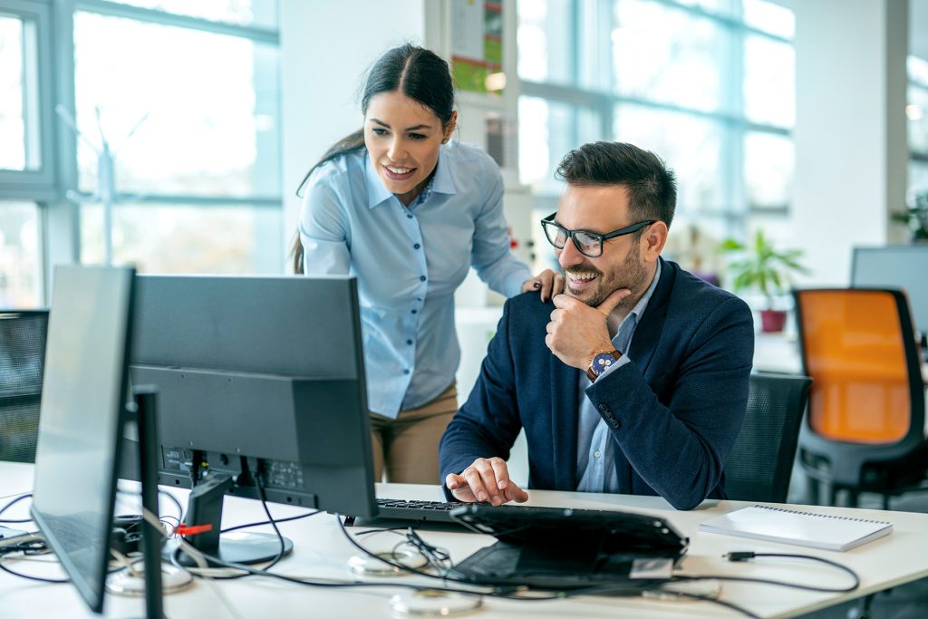 Man and woman collaborating on a problem while looking at a computer monitor.